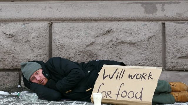 
4K.  Homeless  adult man  lie in  city winter  street,  approach of focus
