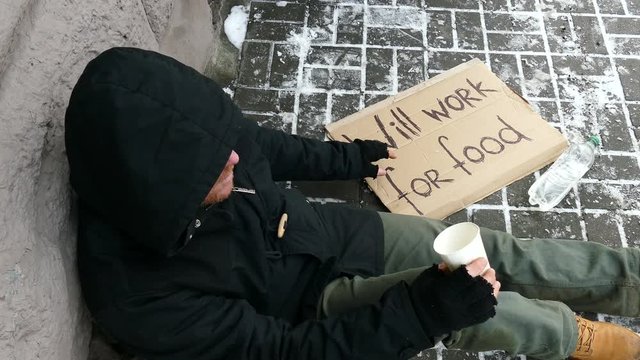 
4K.  City winter  street and homeless  unemployment adult man consider cents. Top view
