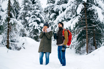 Fototapeta na wymiar Couple in love drink hot tea on a walk in winter forest