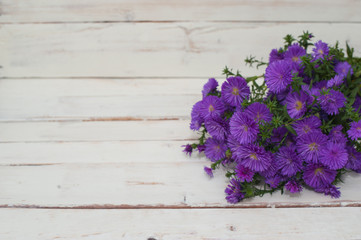Fototapeta na wymiar Pretty violet bouquet on white wooden background