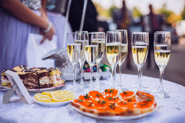 Glasses of champagne on table served for buffet catering party outdoors, close up