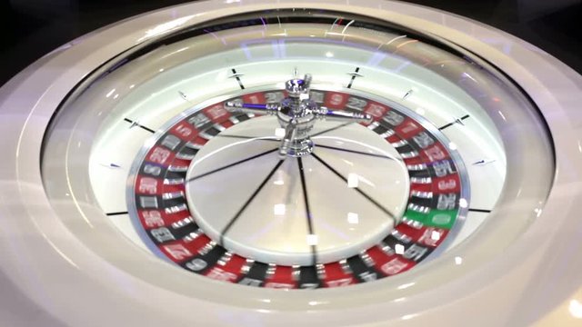 Modern roulette table in casino. Ball in the rotating gambling machine. Colourful roulette wheel.