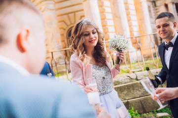 Bride and groom with happy groomsmen and bridesmaids having fun and popping champagne, luxury...
