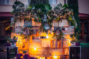 Beautiful unusual wedding decor. Rustic Style. Bench, wall of flowers, lanterns at the photo zone.