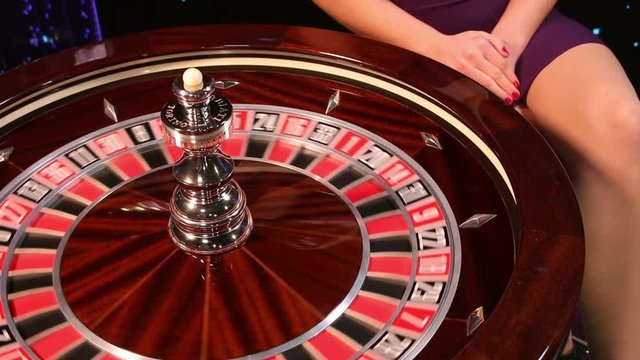 Casino roulette in motion, the spinning wheel ball and croupier hand