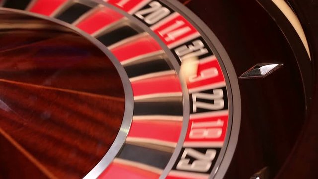 Casino roulette in motion, the spinning wheel ball and croupier hand