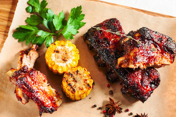 Grilled pork ribs with corn on wood flat lay. Top view on catering platter with hot barbecue meal. Junk food, restaurant menu, snack for beer concept