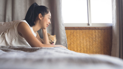 Woman relax with dog in bedroom.