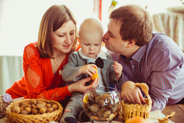The mother,father and son sitting near table with nuts