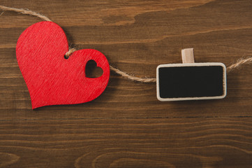 red heart on a rope and small blackboard on a wooden background