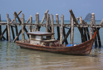Shabby wooden boat anchored near rough wooden pier, Langkawi
