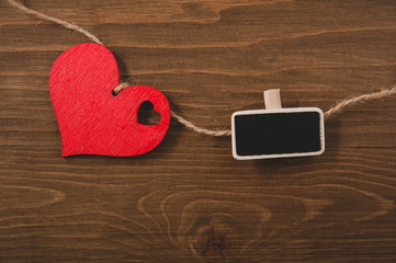 red heart on a rope and small blackboard on a wooden background