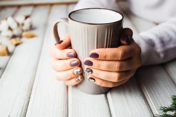 Woman with beautiful manicure holding a gray cup of tea