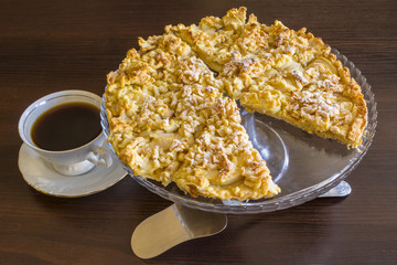 Apple charlotte in a large glass vase. With a cup of black coffee and a shovel for a cake. Still  life. Polish  cuisine..