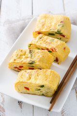 Traditional tamagoyaki Japanese omelette on white wooden table.
