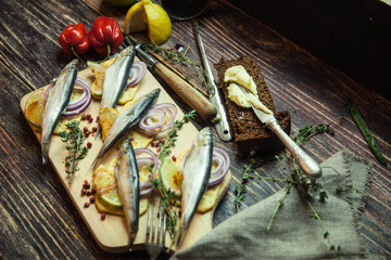 Fresh fish with aromatic herbs, spices, salt, onion rings, bread, bottles with olive oil and balsamic vinegar,perch on cracker, on dark vintage background, top view, healthy food