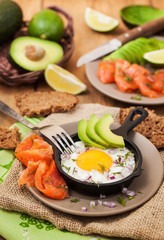 Fried egg, avocado and smoked salmon in frying pan