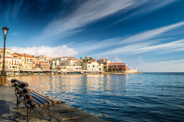 CHANIA, CRETE - JUNE 26, 2016: View of the old venetian port of Chania on Crete island, Greece. Tourists relaxing on promenade.