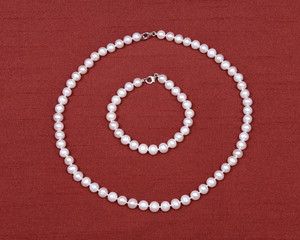 Freshwater pearl necklace on red fabric background