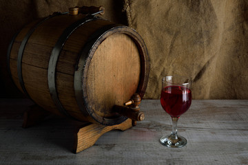 cask of wine on a wooden background with a glass of wine
