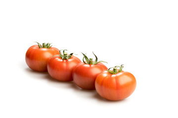 Four realistic looking fresh red tomatoes lying in a line isolated in a white background