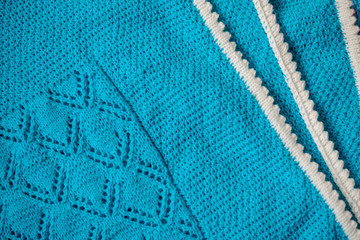Blue baby blanket with a white border, hand-knitted
