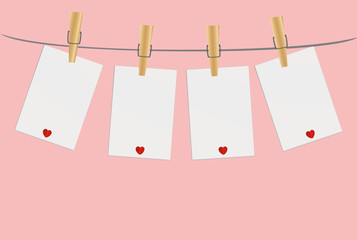 Four blank paper with red heart hanging on the wooden cloth pegs