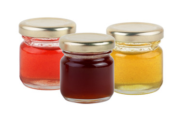 3 jars of multi-colored jams and honey isolated on white background.
