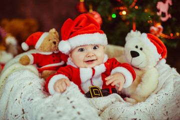 The small boy has a red  costume and  sitting on the basket