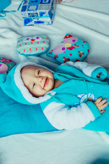 The small boy has a blue costume and  lies on the bed