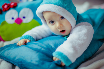 The small boy has a blue costume and  lies on the bed