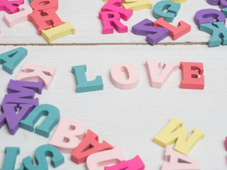 Fototapeta premium Vanlentine's day concept. Wooden color letters word love and red heart on color background with copy space.watering can love concept.