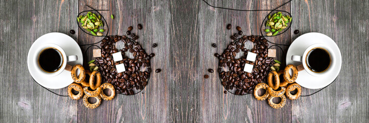 Coffee cup, coffee beans, cardamon seeds, dried biscuits, sugar cubes on wooden table, Top view. Wide panoramic image.