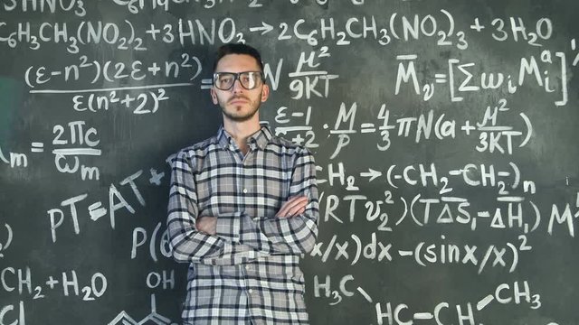 Young scientist man posing in chemical and mathematical equations wall room interior
