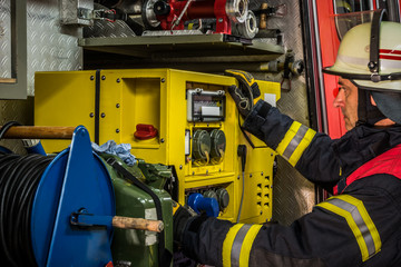 HDR - Feuerwehrmann im Einsatz am Einsatzfahrzeug und bedient den Stromgenerator
