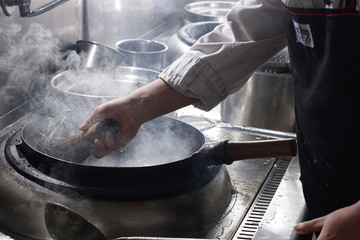 Cleaning wok with wooden sticks and metal wire