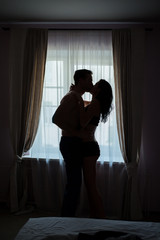 Couple kissing and hugging. Man and woman beside window. Don't restrain your passion.