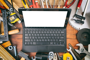 Hand tools and laptop on wooden background