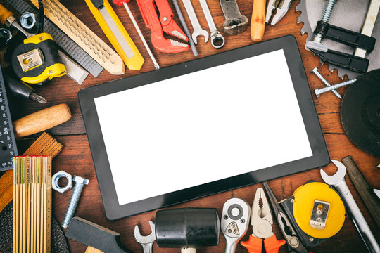 Hand tools and tablet on wooden background