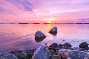 Picturesque sea landscape with large stones at foreground. Violet toning. Color in nature concept.