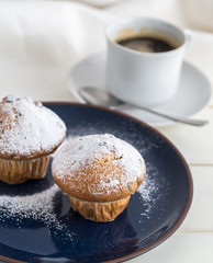 Breakfast with muffins by powdered sugar and coffee.