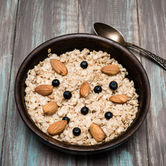 Healthy breakfast: oatmeal porridge with muesli, blueberries, almonds.