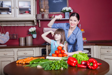 Happy mother and daughter enjoy making and having healthy meal together at their kitchen. they are making vegetable salad and having fun together. mom take care of her daughter and tech how to cook.
