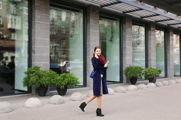 Young beautiful businesswoman talking on phone beside office building