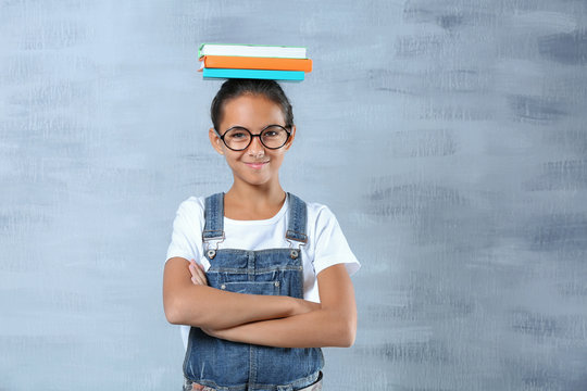 Cute girl with books on color background
