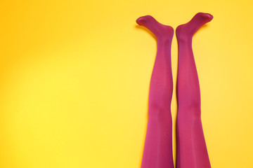 Beautiful woman legs in color tights on yellow background