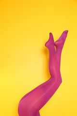 Obraz premium Beautiful woman legs in color tights on yellow background