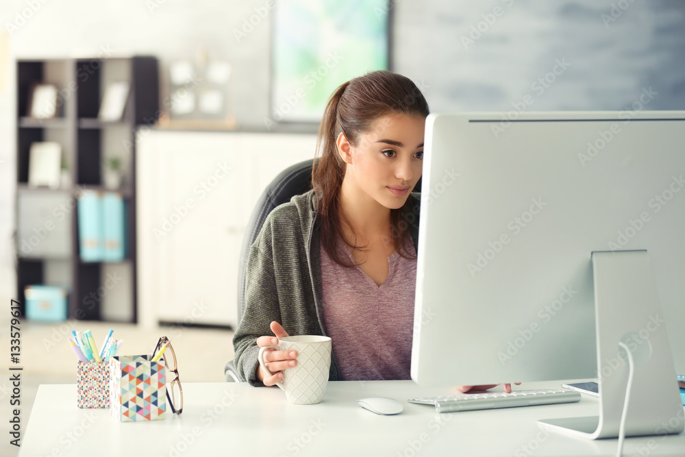 Wall mural Beautiful young woman working in office