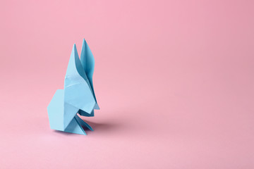 Origami paper bunny on pink background