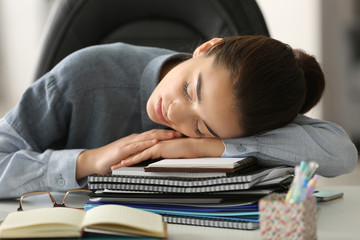 Tired young woman sleeping in office